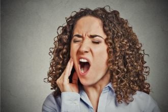 A woman with TMJ dysfunction holding her right jaw