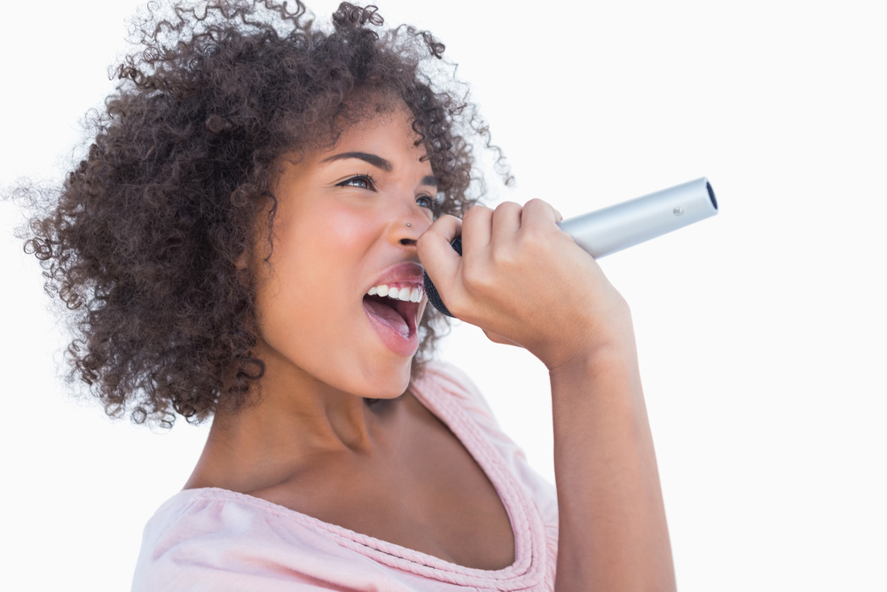 A woman singing into a microphone with hyoid tightness