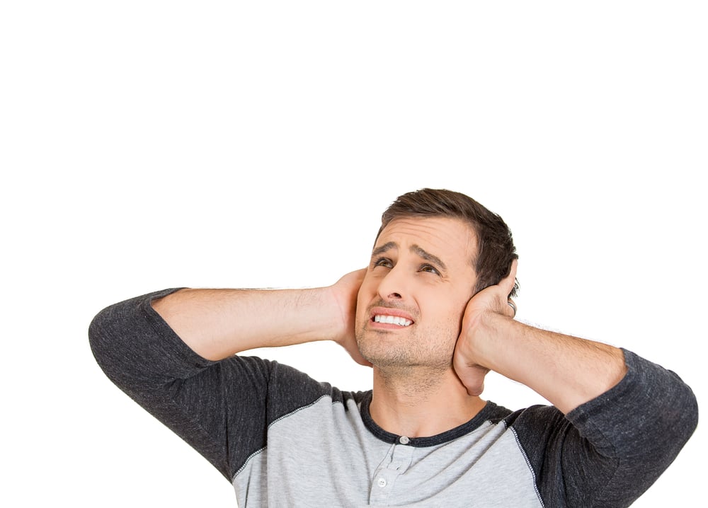 Man covering his ears, bothered by ringing linked to his jaw and neck