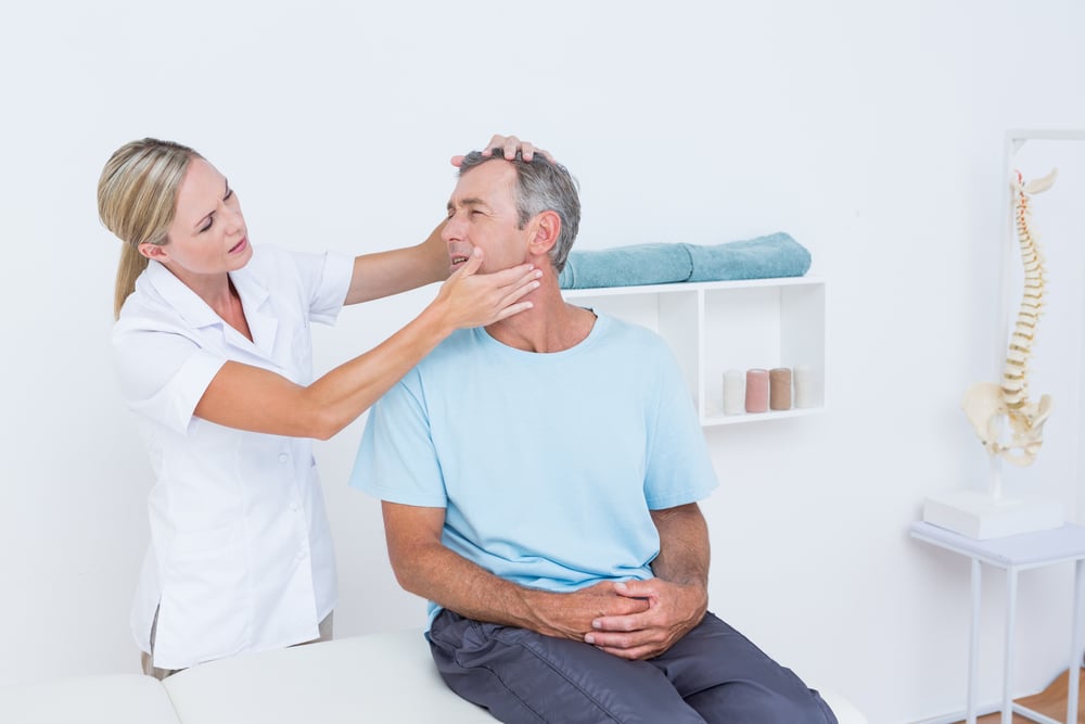 Physical therapist providing hands-on neck treatment as part of TMJ dysfunction care