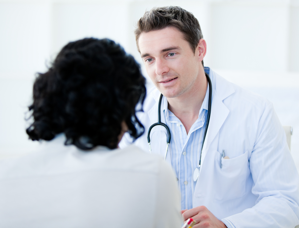 Handsome doctor talking with his patient for the annual check-up in the hospital