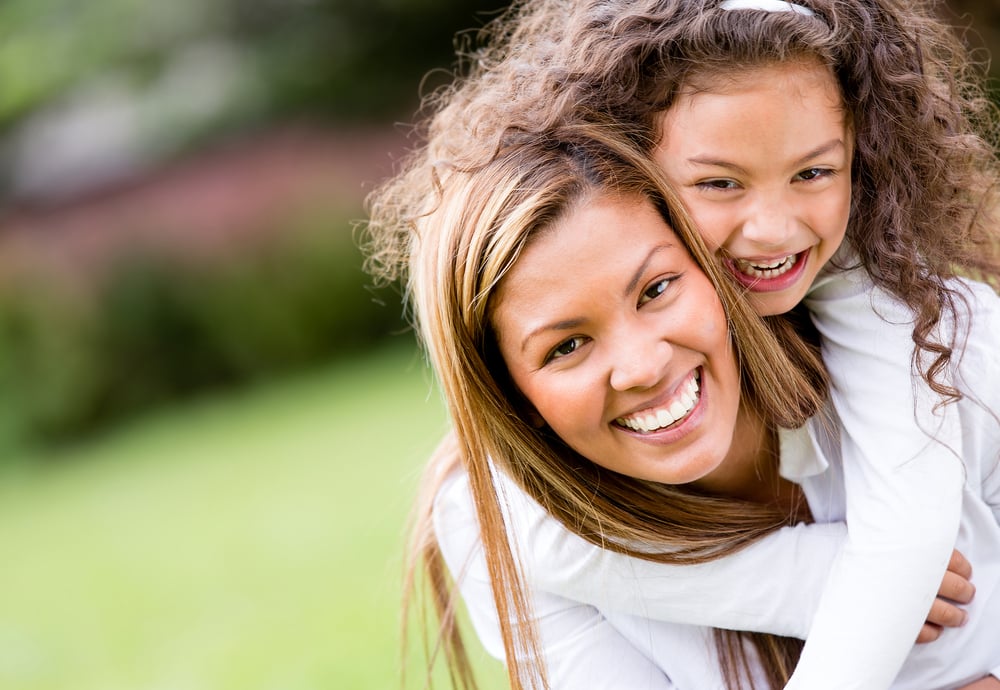 Mother and daughter laughing together outdoors, free of headaches after TMJ physical therapy