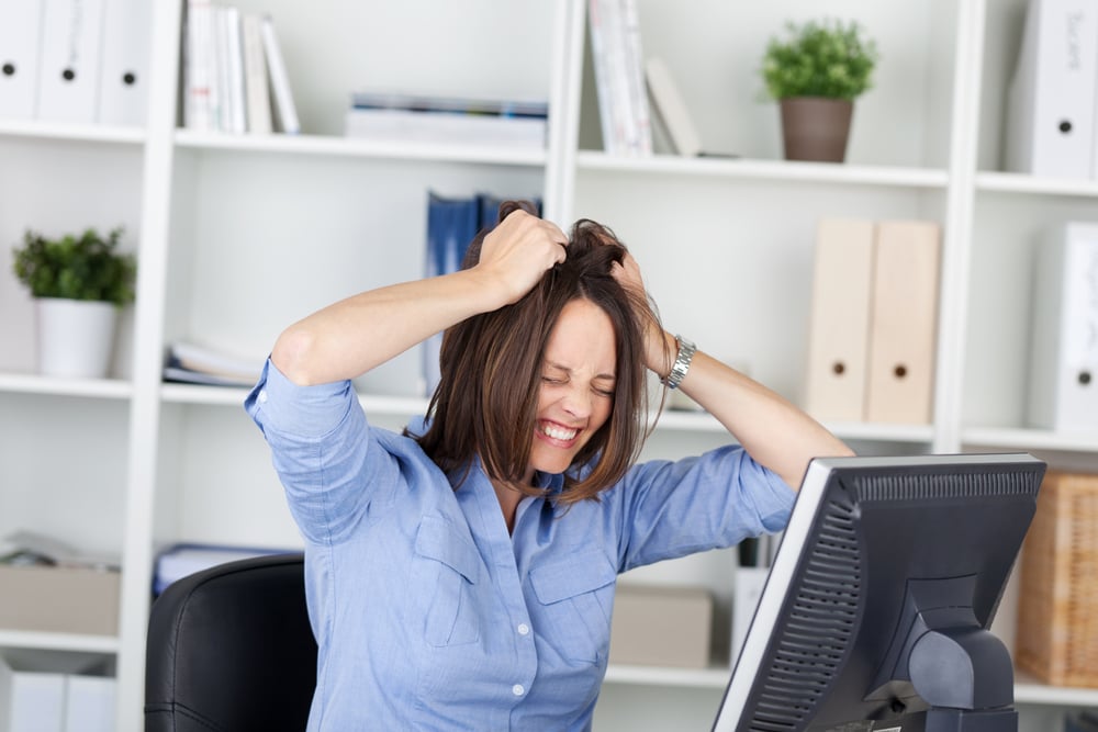 Stressed woman clenching her jaw while working at her laptop