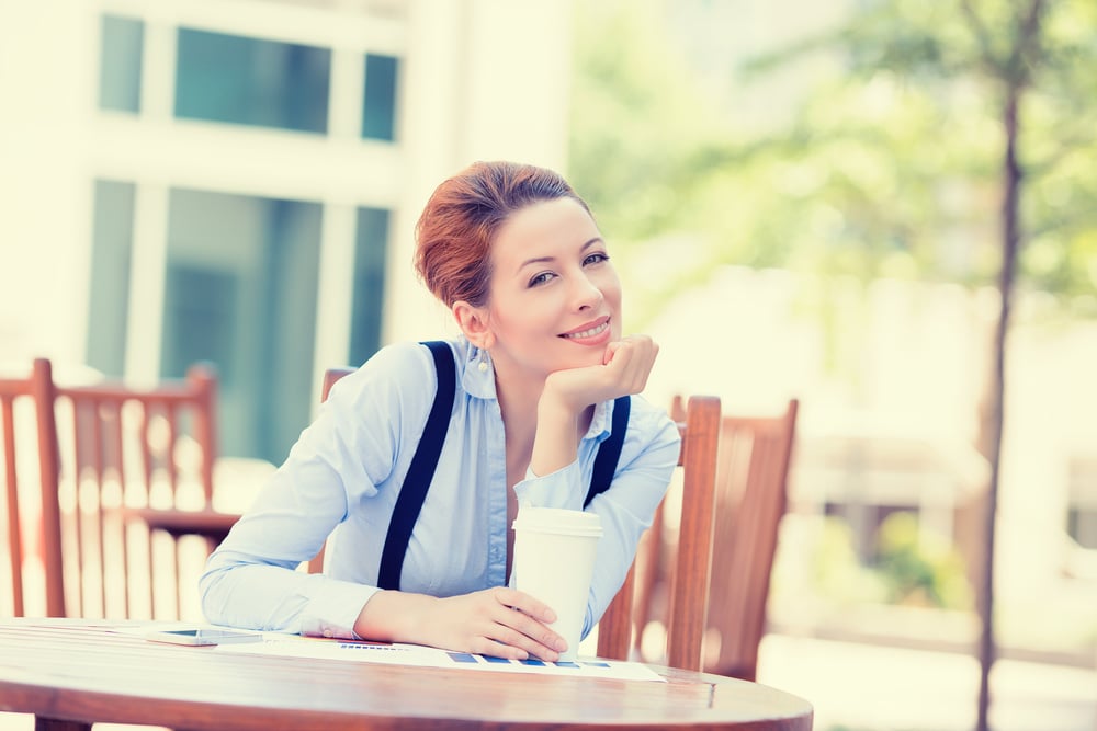 Relaxed woman enjoying a quiet morning coffee in the sun after physical therapy for somatic tinnitus