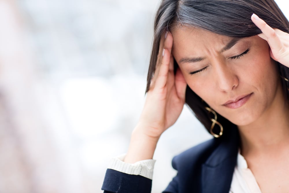 Woman pressing her temples with a headache caused by a TMJ disorder