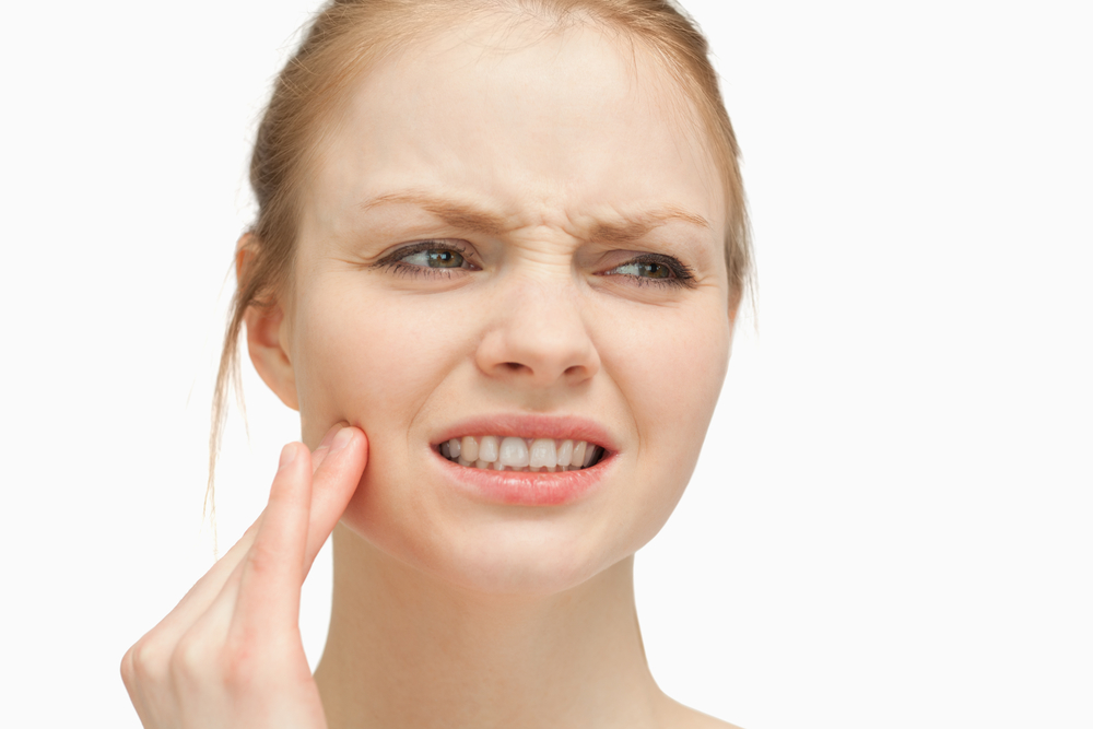 Woman massaging her cheek against white background-1 Woman massaging her cheek against white background-1