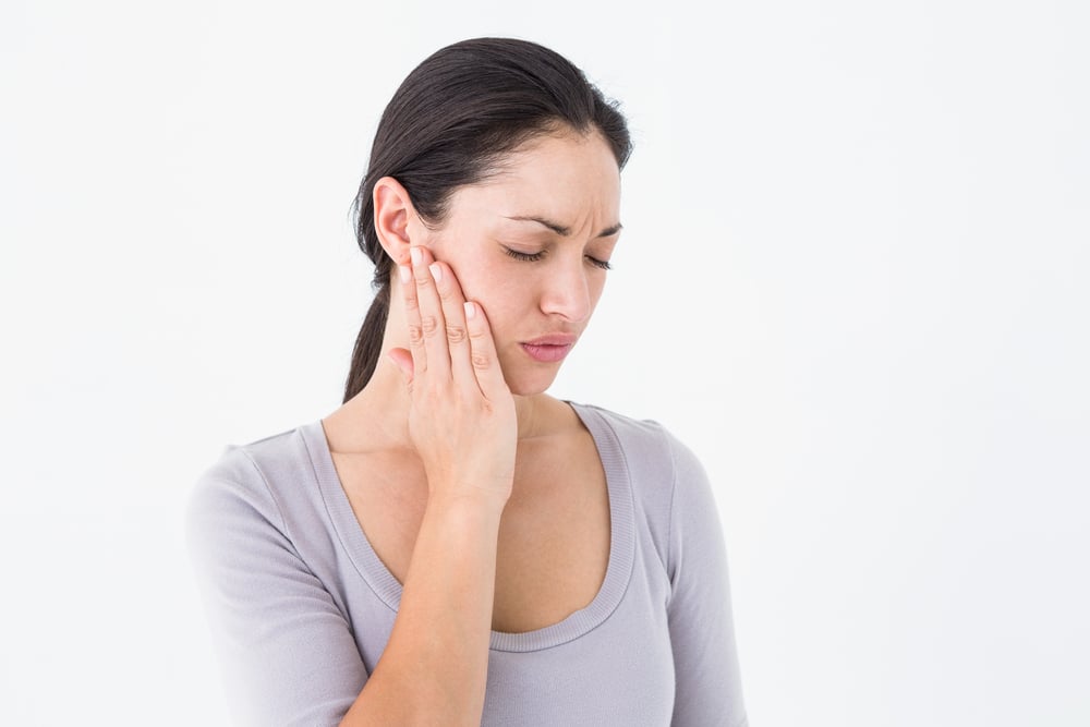 Woman holding her jaw in discomfort from a clicking TMJ disorder